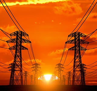 The sun rising behind an array of electricity towers.